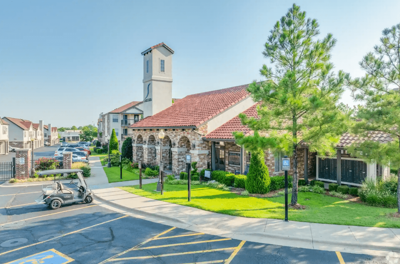 A church with a clock tower is surrounded by a parking lot.